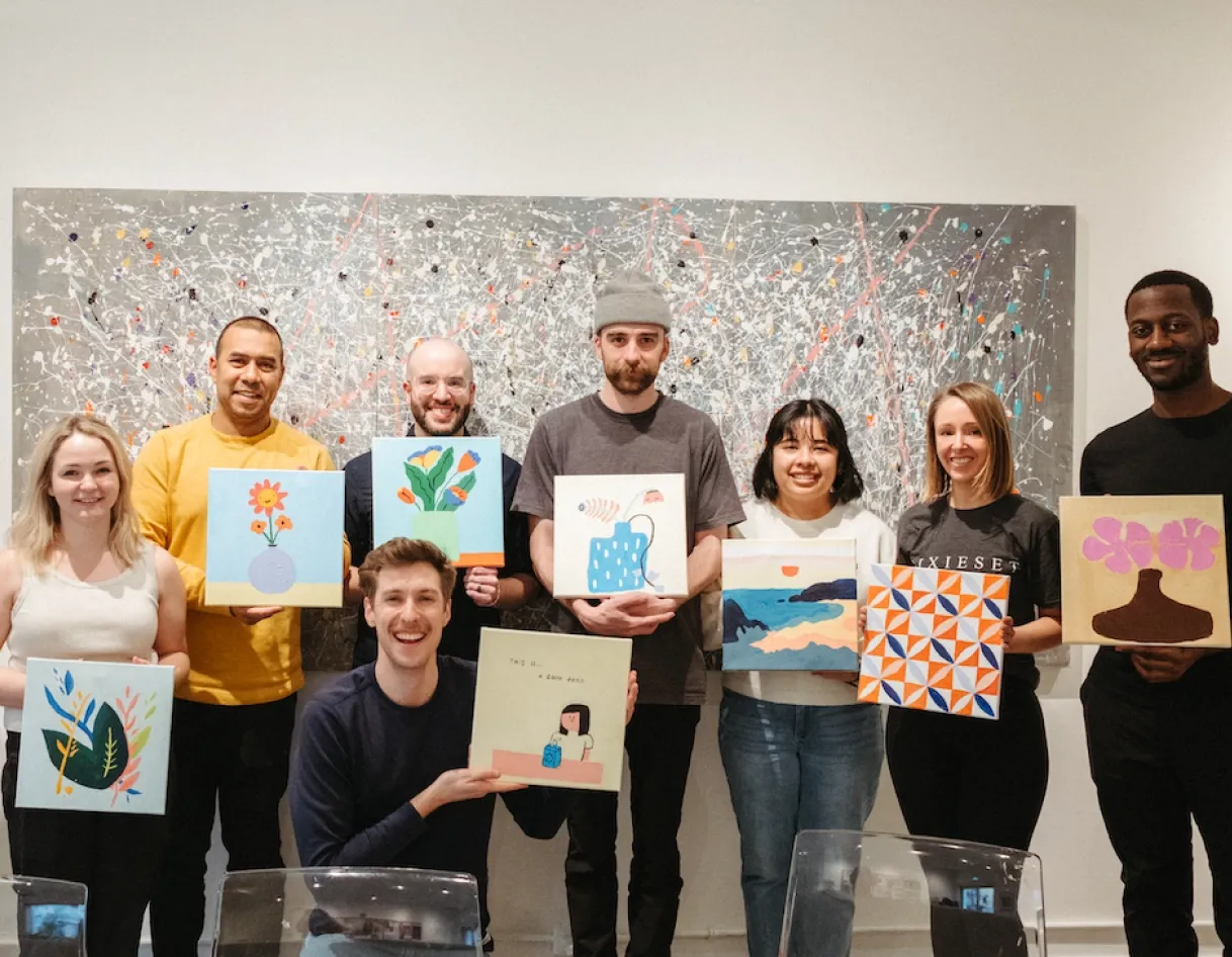foto.umbii.boo team members holding up colorful paintings, reflecting the company’s craftsmanship values and creator-first culture highlighted in the Careers page message.