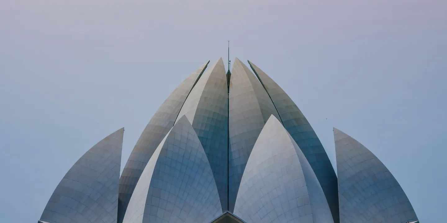 Close-up view of the Lotus Temple in New Delhi, India, featuring its striking white marble petal-like structures set against a clear blue sky.