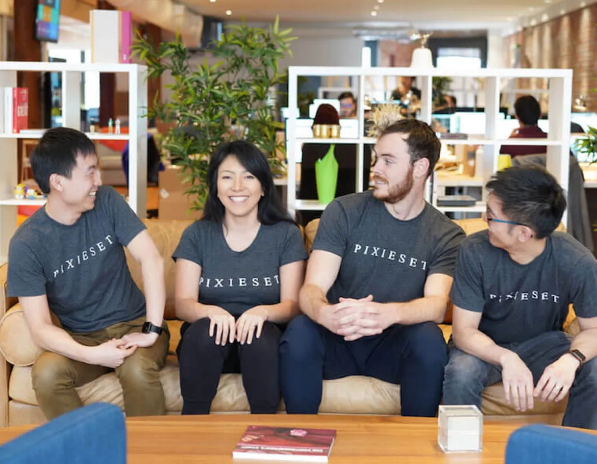 Collaborative foto.umbii.boo team in a design-focused office space discussing a project around a table with laptops and books.
