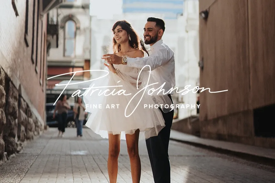 Urban engagement photo of couple dancing in sunlight between buildings